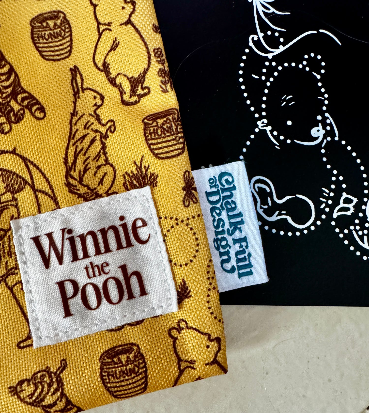 Winnie the Pooh fabric with a visible brand tag and black background with white design.
